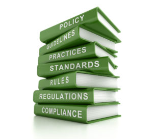 A stack of green books with the titles Policy, Guidelines, Practices, Standards, Rules, Regulations, and Compliance