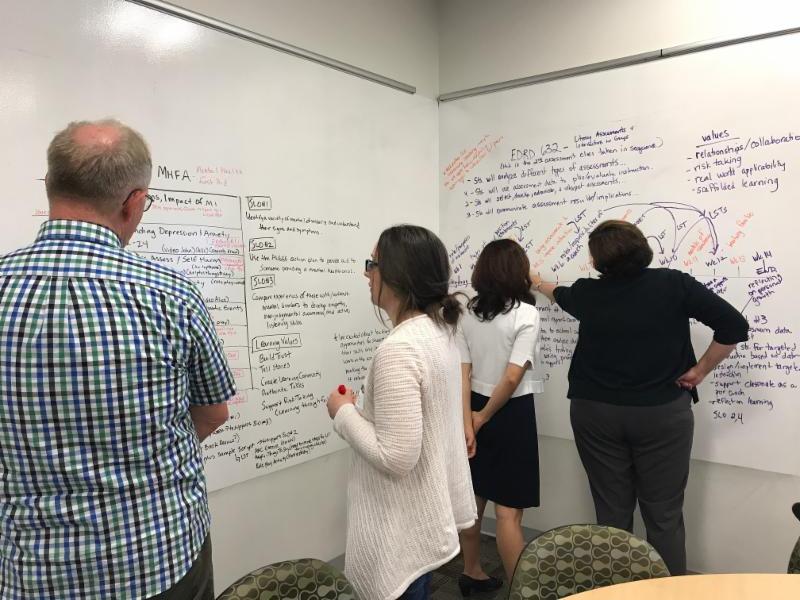 Four people studying a large whiteboard